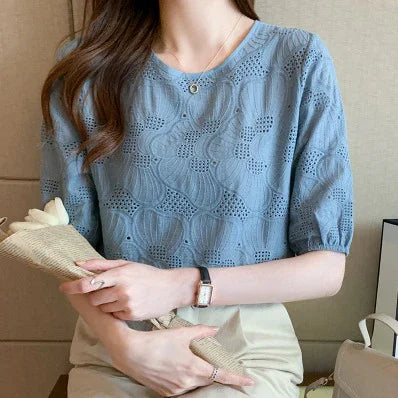 Woman wearing blue eyelet lace blouse with short sleeves, holding wrapped white flowers