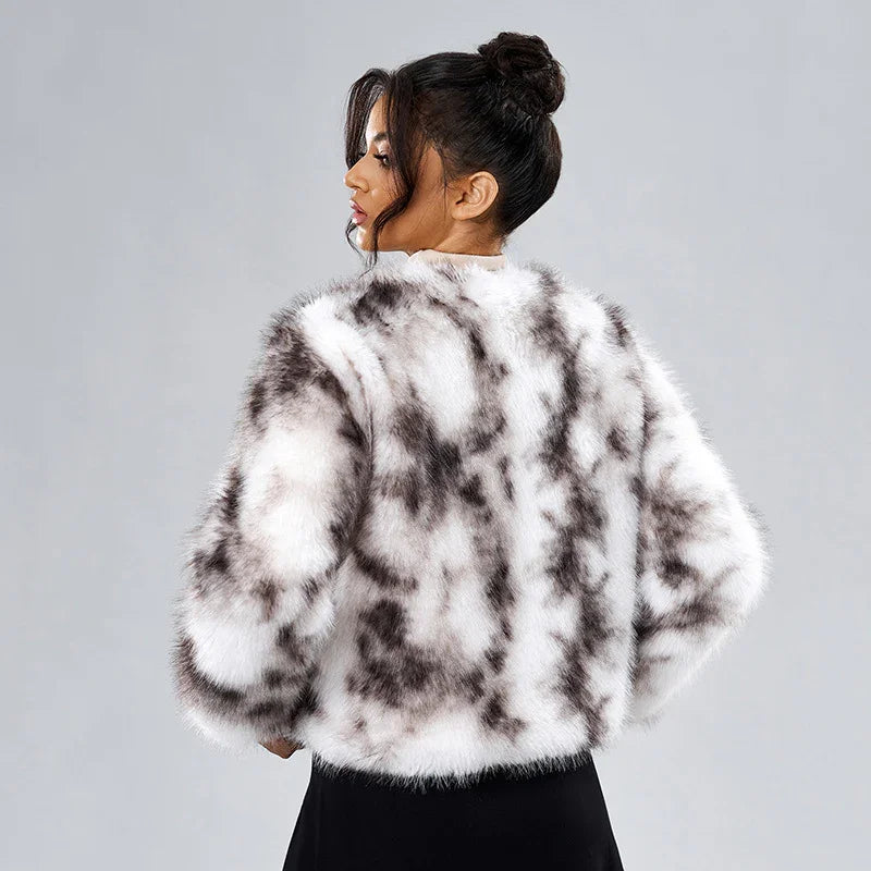 Woman wearing a white and black spotted faux fur jacket with hair in a bun on gray background