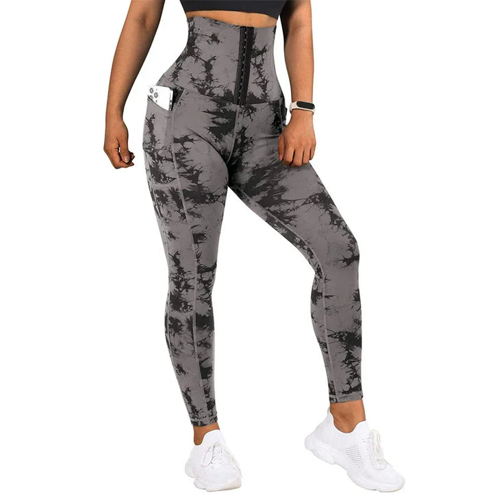 Woman wearing high-waisted gray and black tie-dye leggings with side pockets and white sneakers