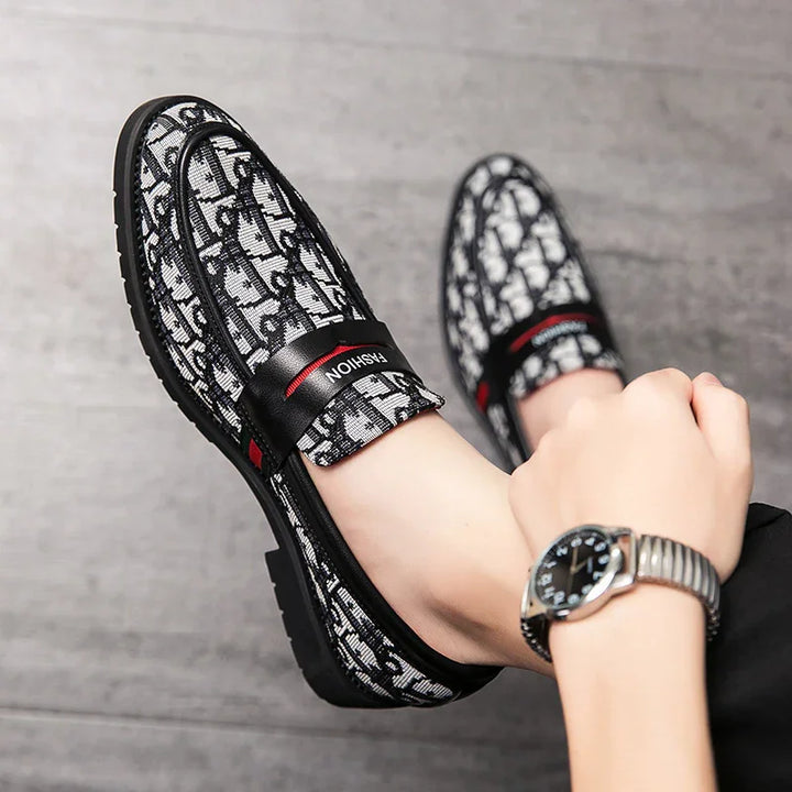 Black and white patterned slip-on men's shoes with black strap labeled FASHION on gray floor