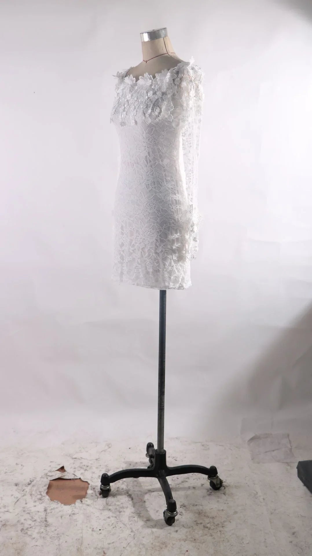 White lace long-sleeve dress on a vintage dress form mannequin with a plain white background