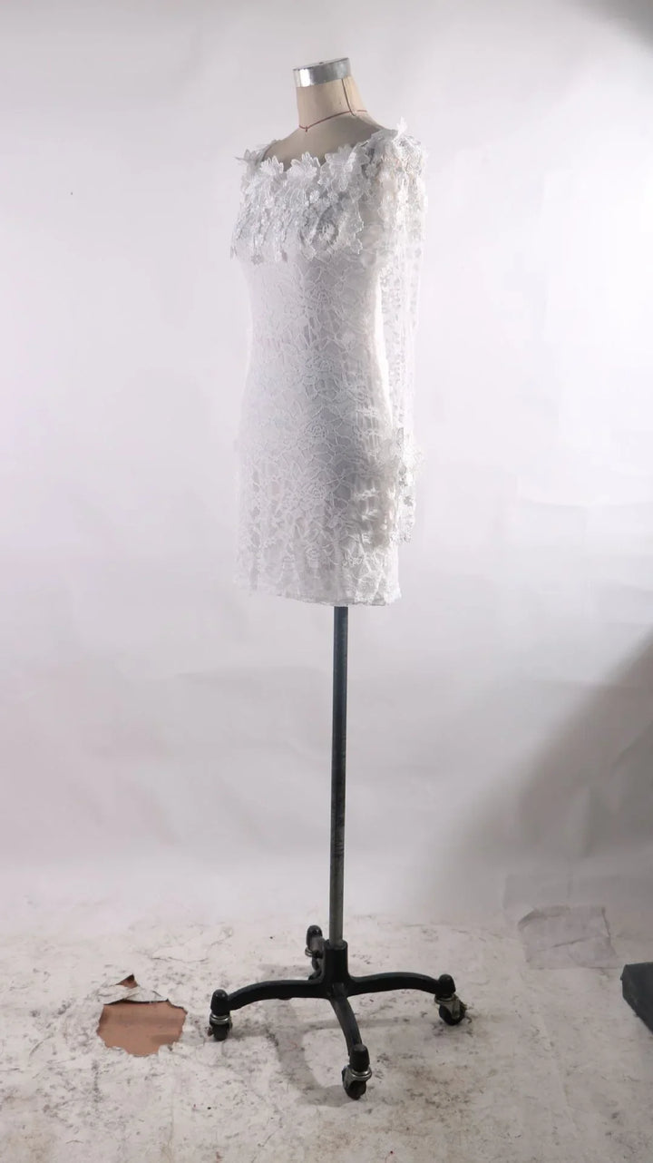 White lace long-sleeve dress on a vintage dress form mannequin with a plain white background