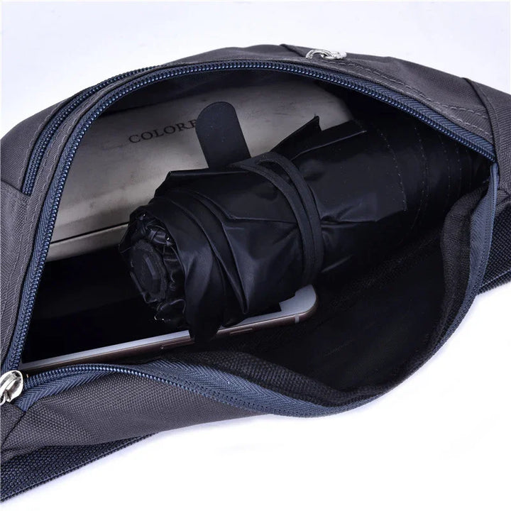 Open black sling bag with rolled black umbrella and smartphone inside