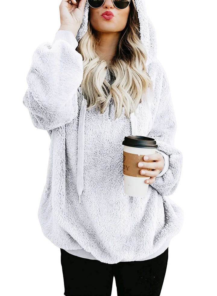 Woman in fluffy white hoodie with sunglasses and blonde hair holding coffee cup