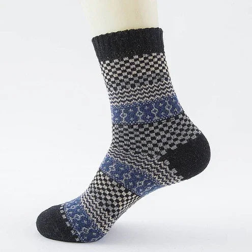 black, gray, and blue patterned wool sock with checkered and snowflake designs on white background