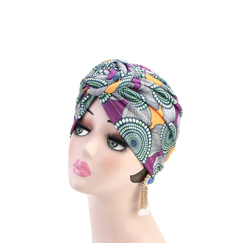 Mannequin head wearing colorful turban headwrap with circular patterns and long chain earrings