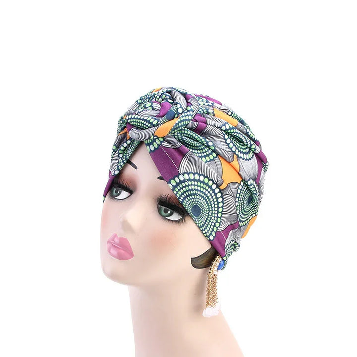 Mannequin head wearing colorful turban headwrap with circular patterns and long chain earrings
