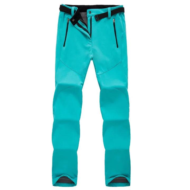 Turquoise softshell outdoor pants with black zippered pockets and adjustable waist belt