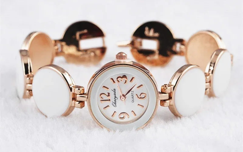 elegant rose gold wristwatch with white circular links and quartz movement on white background