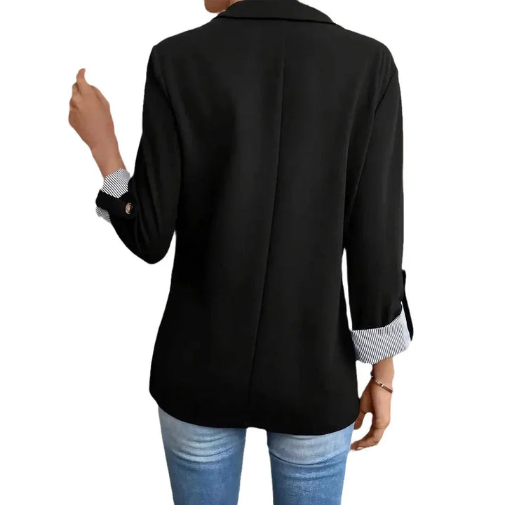 Back view of person wearing black blazer with rolled striped cuffs and blue jeans