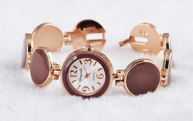 Rose gold ladies quartz wristwatch with brown circular links and white dial on white fabric