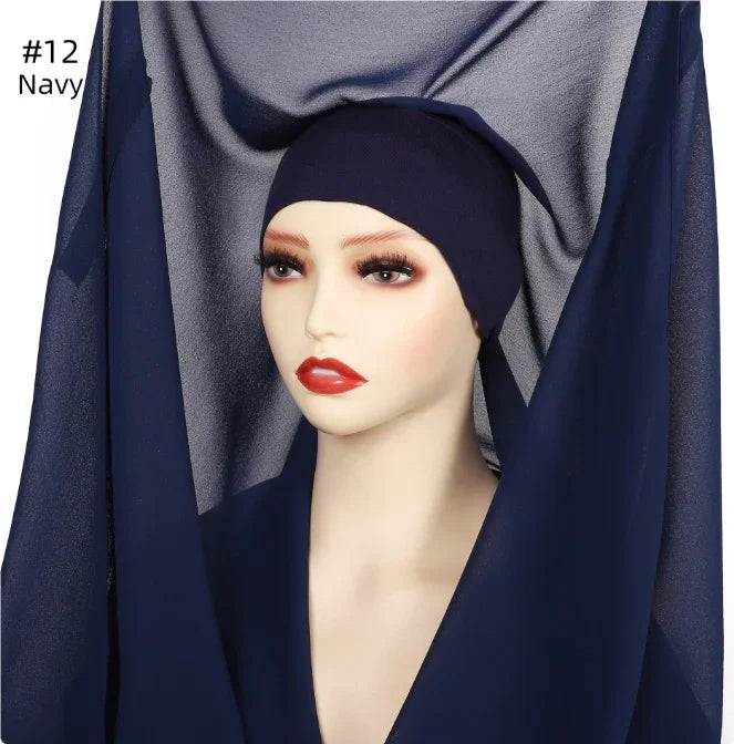 Mannequin wearing navy blue hijab cap with matching navy blue fabric backdrop