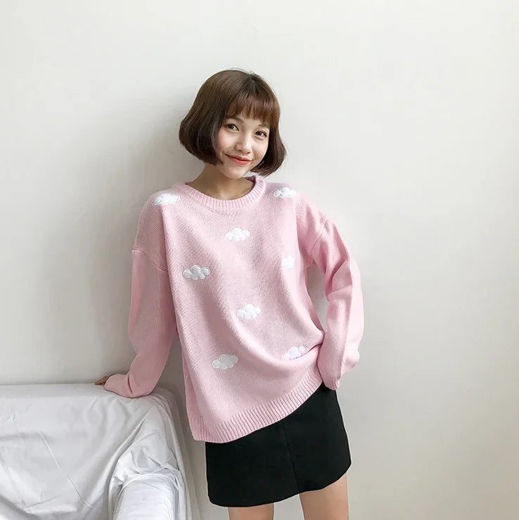 Young woman wearing pink sweater with white cloud patterns and black skirt, posing indoors