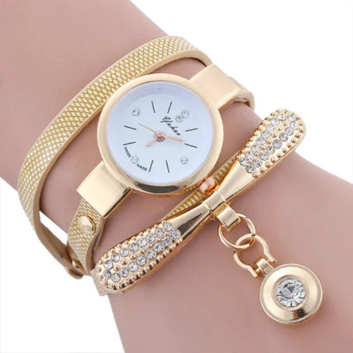 Gold-tone wristwatch with white dial and crystal accents on a textured bracelet and bow charm