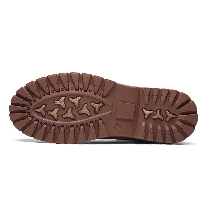 Close-up of brown rubber boot sole with deep treads and geometric traction patterns