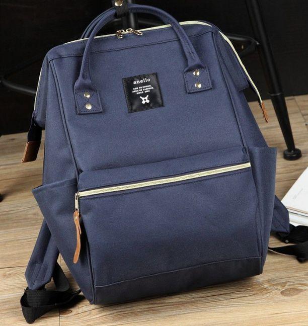 blue Anello backpack with front zipper pocket and leather zipper pulls on wooden floor