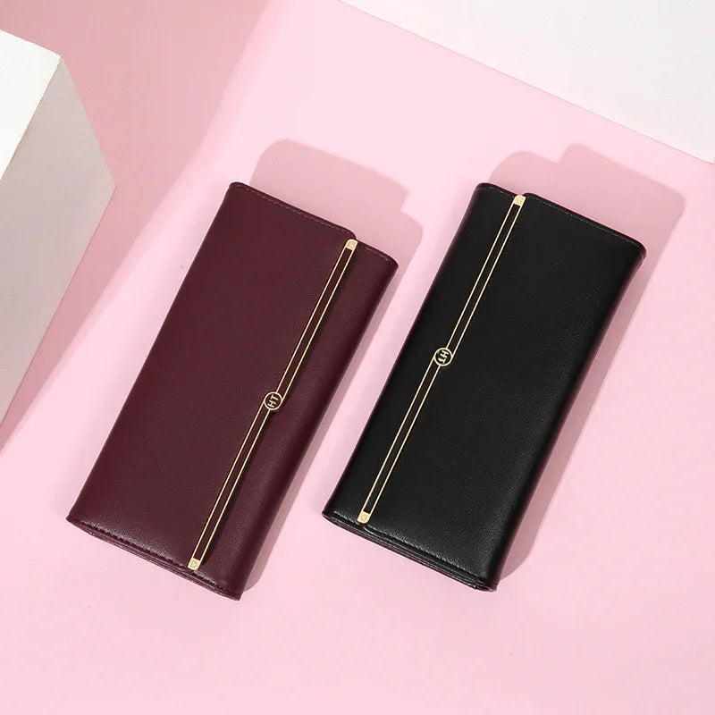 Elegant women's leather wallets in black and burgundy with gold stripe detail on pink background