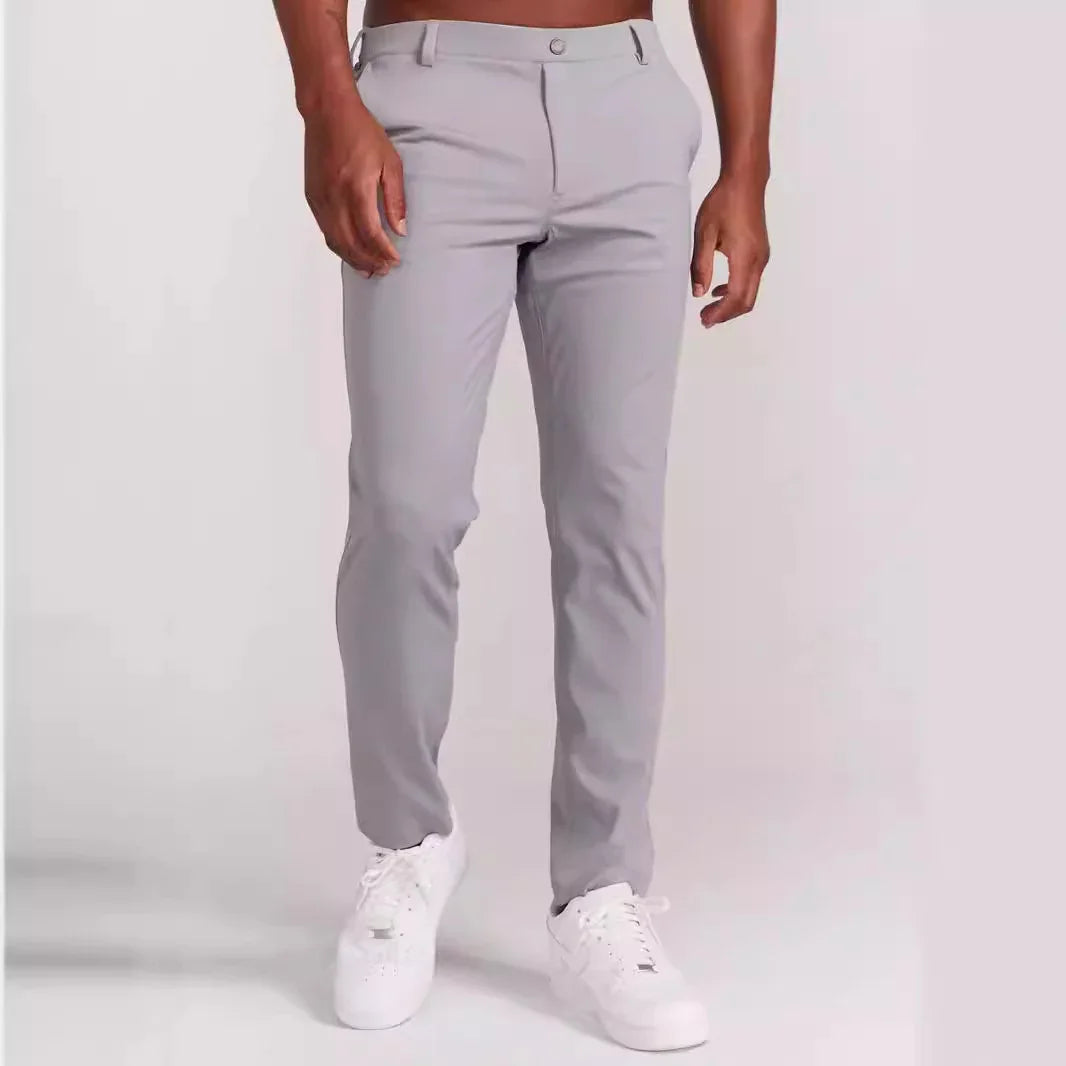 Man wearing slim fit light gray pants and white sneakers against white background