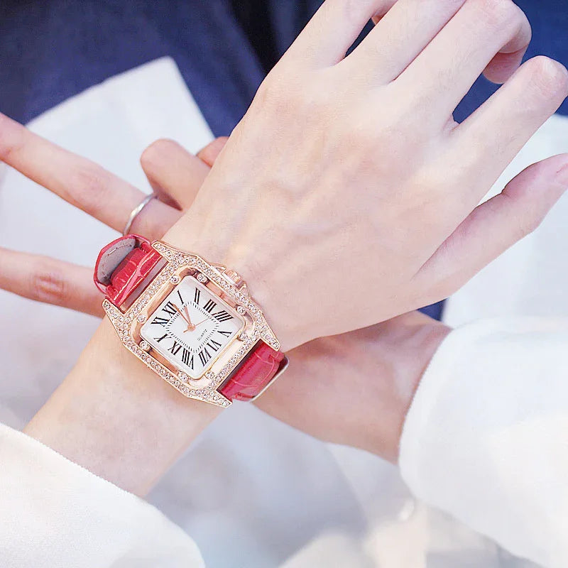 Elegant wristwatch with a red leather strap and diamond-encrusted square gold case on a wrist