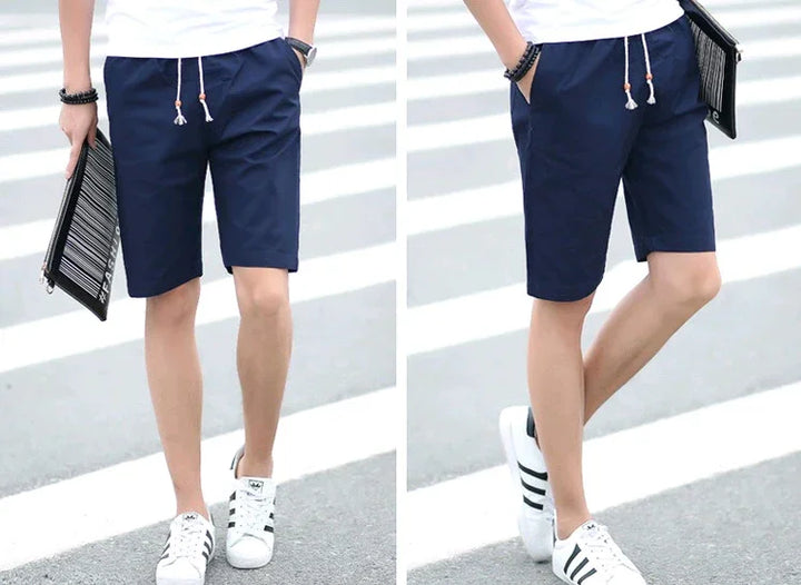 Front and side views of man wearing navy blue casual shorts with white drawstrings paired with white Adidas sneakers