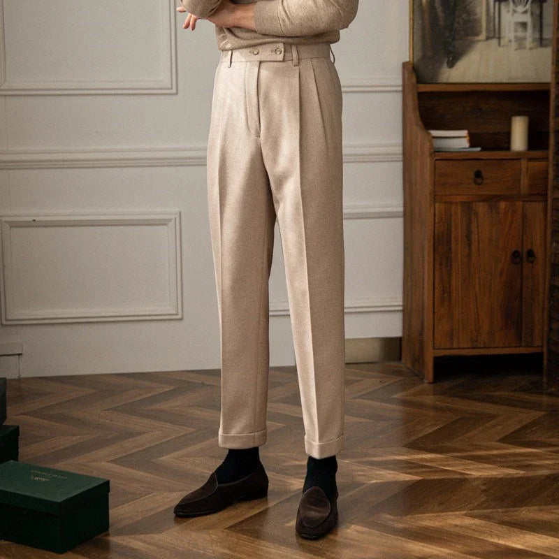 Beige tailored trousers with cuffs worn with dark loafers and black socks in elegant interior