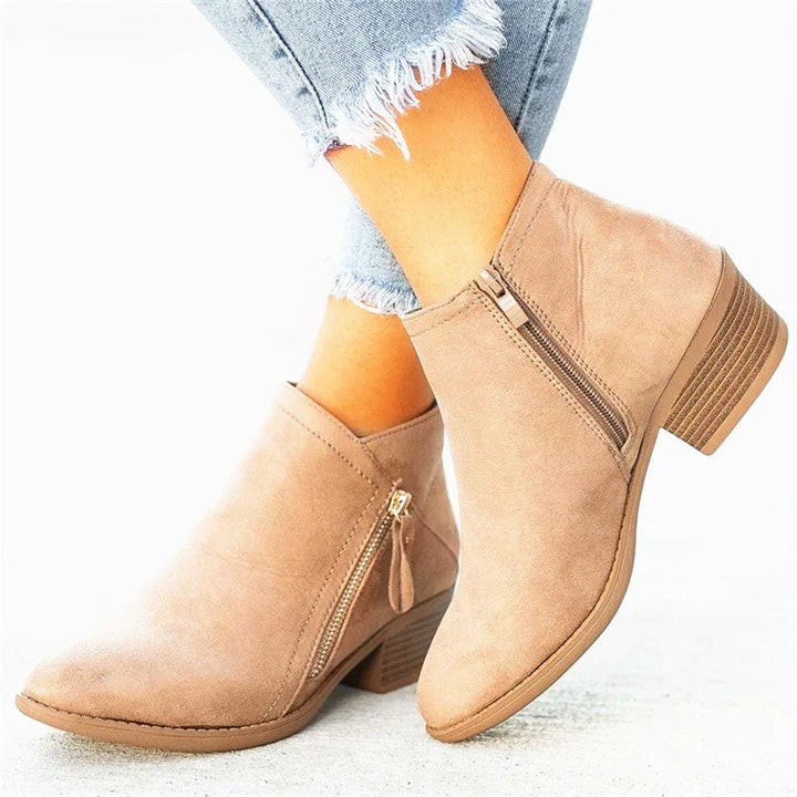 Beige suede ankle boots with side zippers and block heels worn with frayed light blue jeans