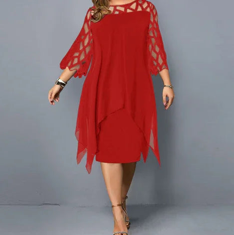 Woman wearing a red knee-length dress with mesh and chiffon overlay, posing against a gray background