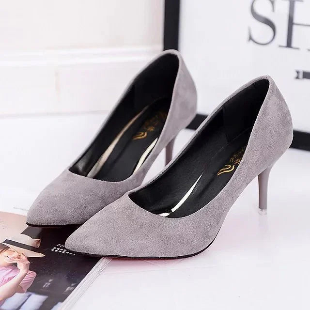 Pair of elegant gray suede high heel pumps with pointed toes on a white surface