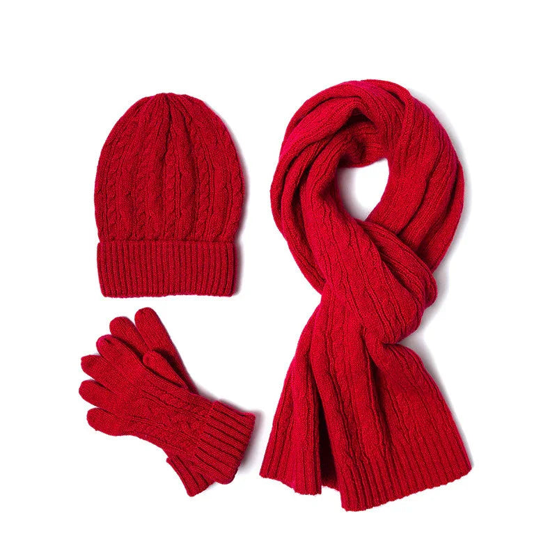 Red knitted winter hat, scarf, and gloves set with cable knit pattern on white background