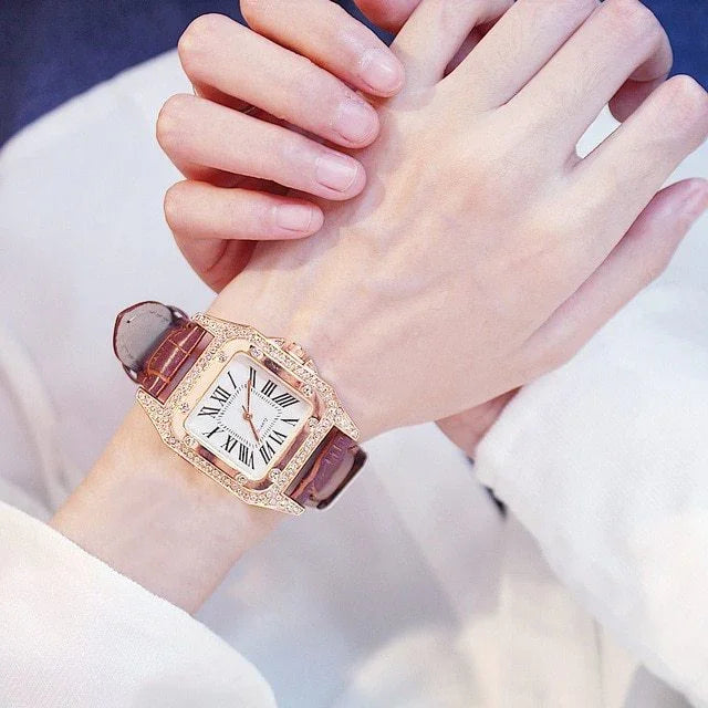 Close-up of hands showing a luxury gold watch with diamond accents and a brown leather strap