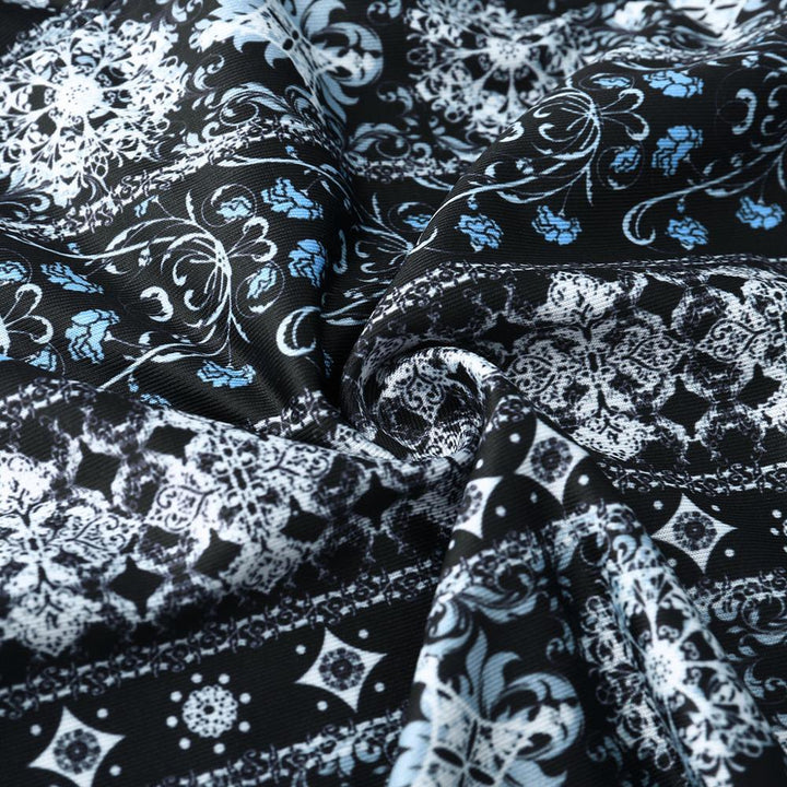 Black fabric with intricate white and blue floral and geometric pattern, softly folded