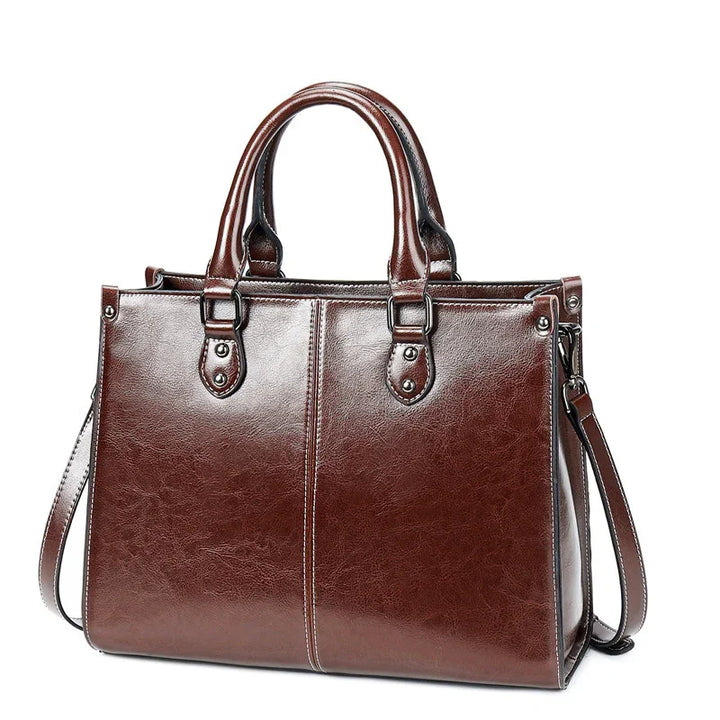 Brown leather handbag with double handles and detachable shoulder strap on white background
