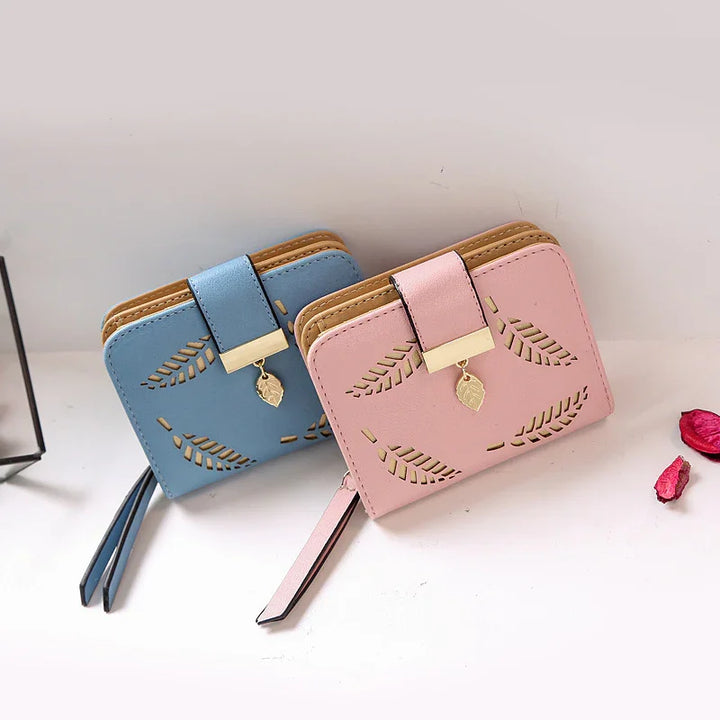 Blue and pink leather wallets with leaf cutout design and gold leaf charm on strap