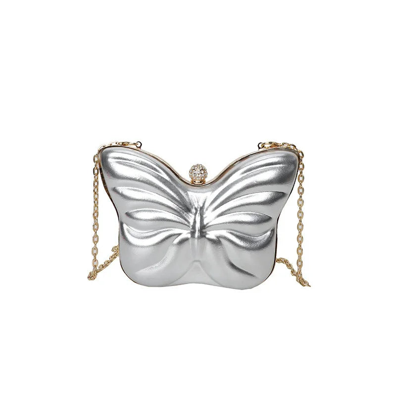 Silver butterfly-shaped clutch bag with a gold chain strap and jeweled clasp