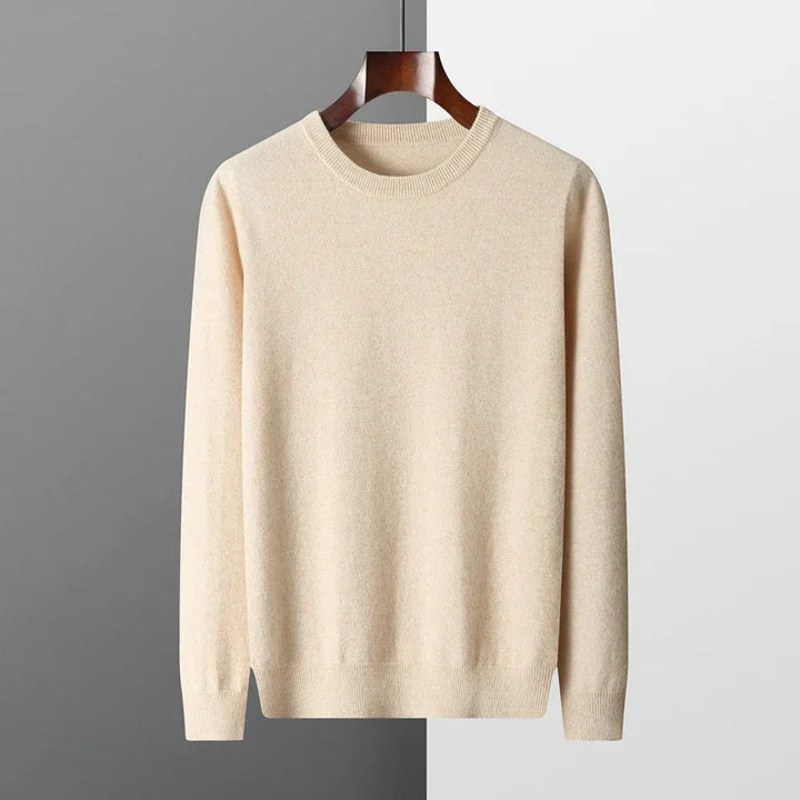 Beige crew neck sweater hanging on wooden hanger against two-tone gray and white background