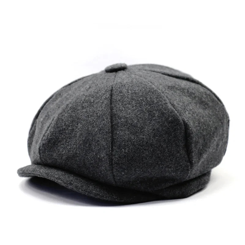 Dark gray wool newsboy cap with paneled design and button on top, isolated on white background