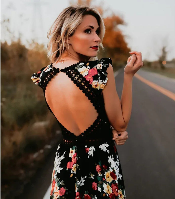 Woman in floral black dress with open back standing on roadside during autumn sunset