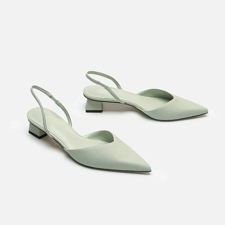 Pair of light green pointed toe slingback low block heel shoes on white background
