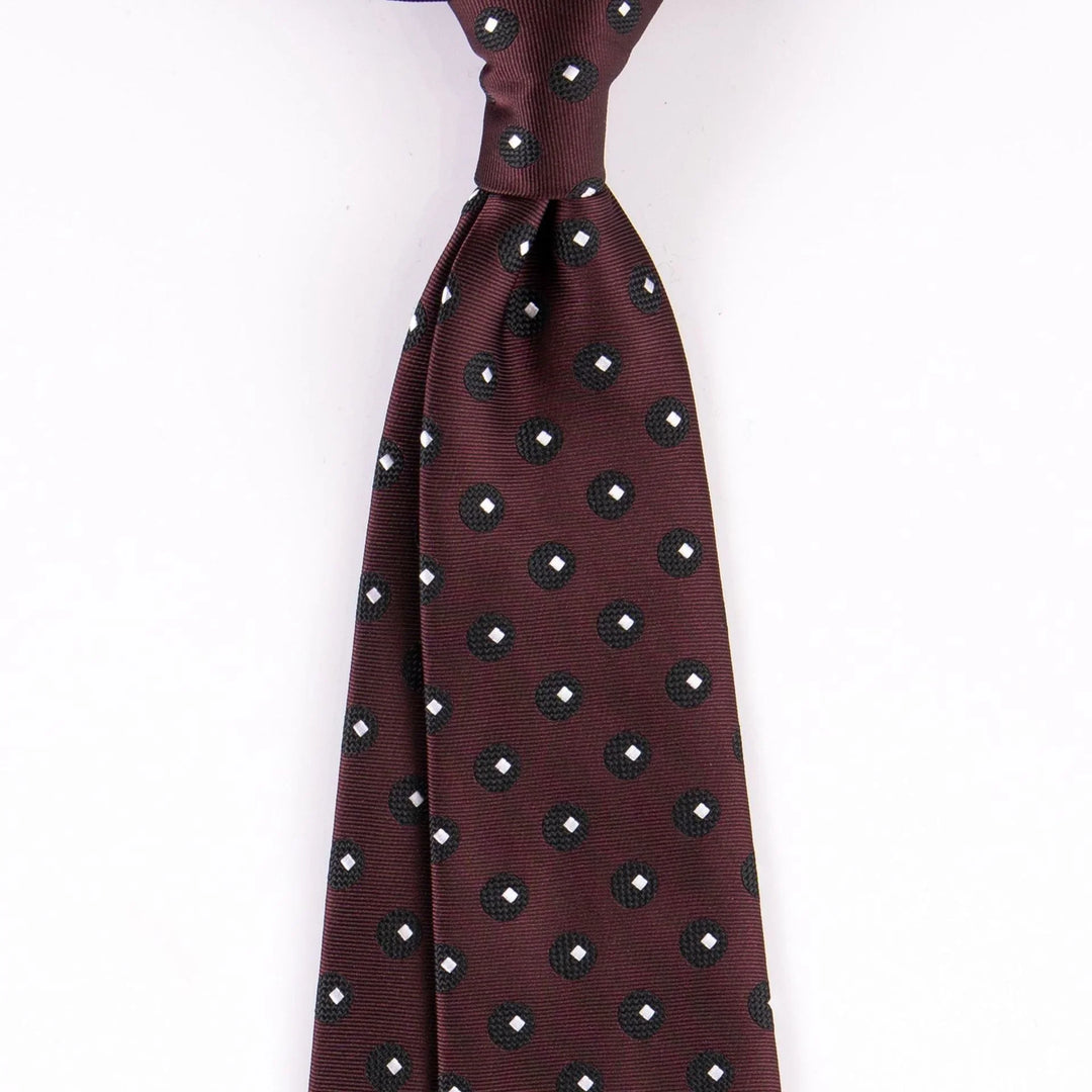 Maroon silk tie with black and white polka dot pattern, neatly knotted on white background