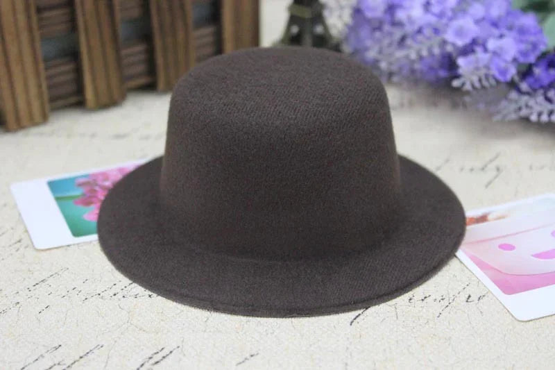 Dark brown wool felt bowler hat on a textured surface with purple flowers and photo cards nearby