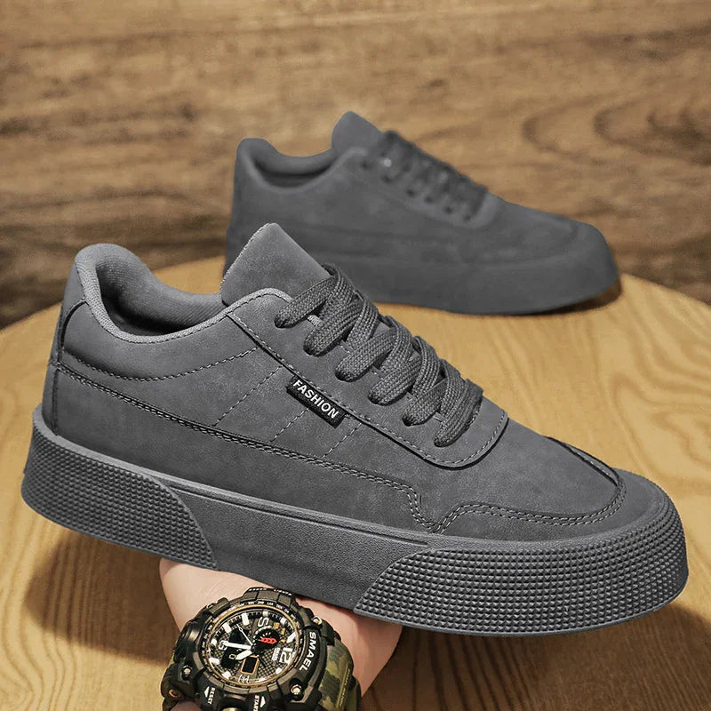 Close-up of gray casual fashion sneakers with thick textured soles on wooden surface