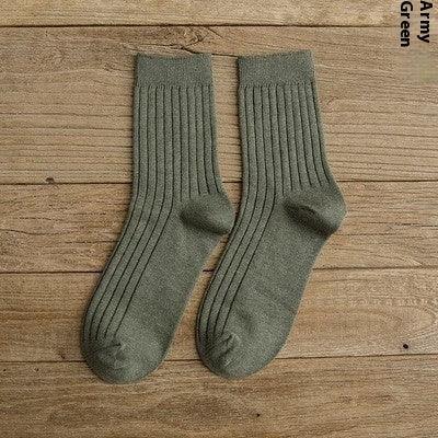 Pair of ribbed army green socks laid flat on wooden surface