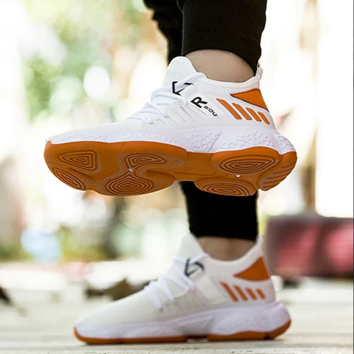 White and orange athletic sneakers with textured sole worn with black leggings outdoors