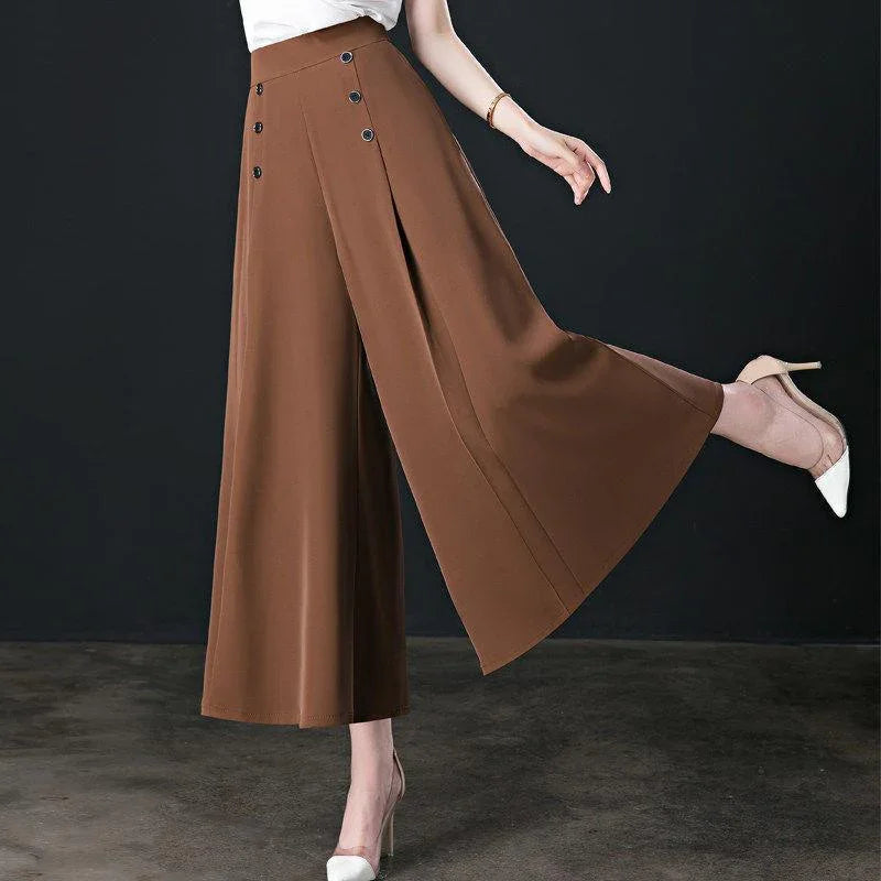 Woman wearing brown wide-leg high-waist trousers with button details, paired with white high heels