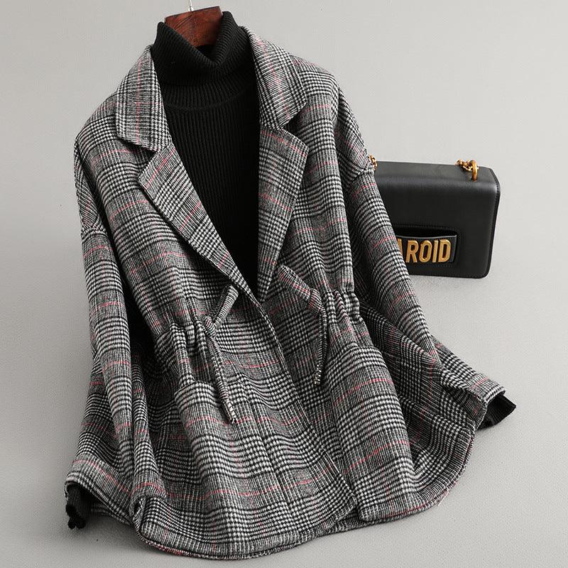 Checked wool blazer with drawstring waist over black turtleneck sweater and black chain shoulder bag