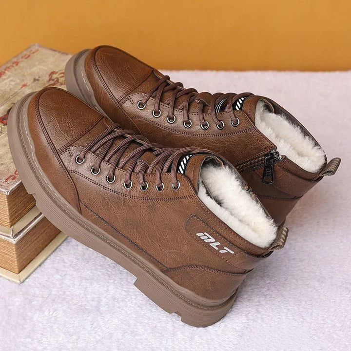 Brown leather lace-up boots with fur lining and side zipper on a light surface with stacked books