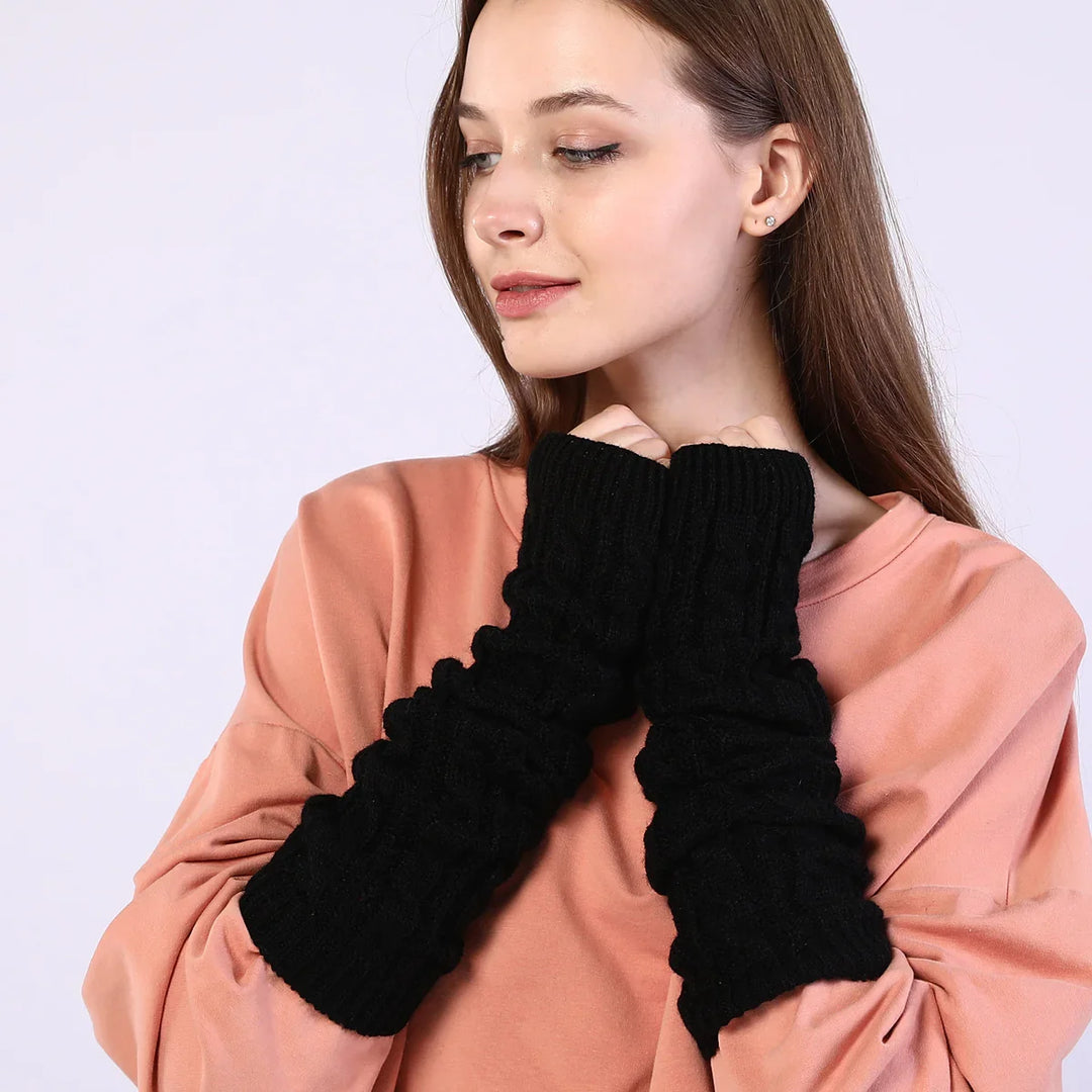 Woman wearing black knitted arm warmers with cable patterns and a peach oversized top