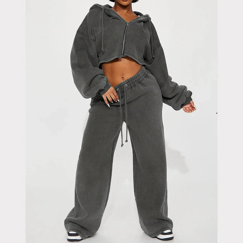 Woman wearing dark gray cropped hoodie and matching wide-leg sweatpants with white sneakers