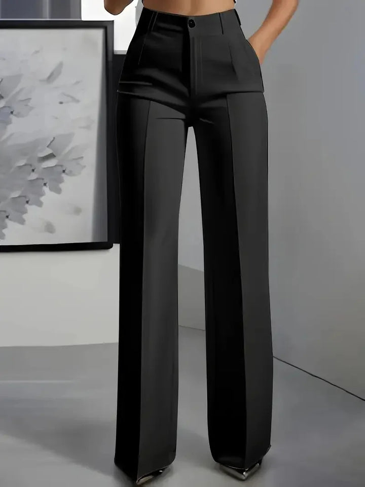 High-waisted black tailored wide-leg pants on model in modern minimalist room