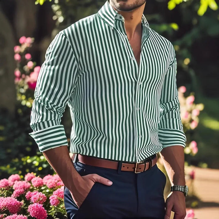 Man wearing green and white vertical striped dress shirt with rolled sleeves, brown belt, and navy pants